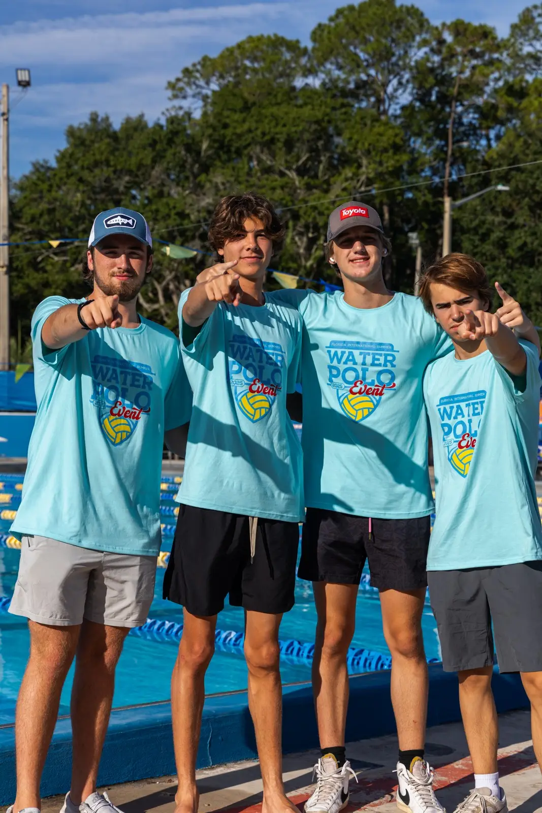 Four summer event coaches in event shirts pointing at the camera