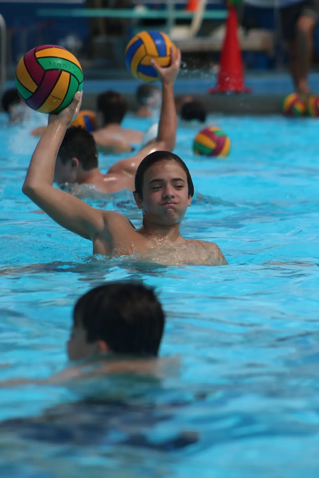 A camper raising the ball to shoot, more balls waiting behind him