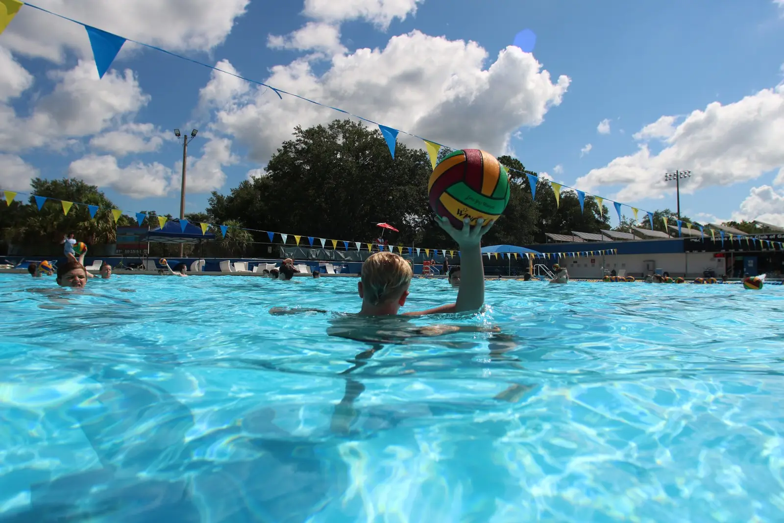 An athlete shooting under summer clouds and pennant flags at the outdoor pool