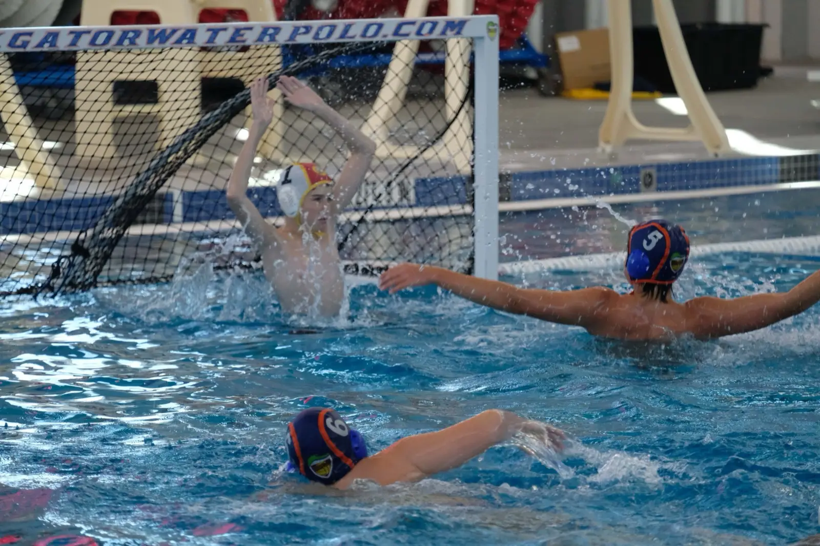 A goalkeeper stretching across the Gator Water Polo cage to stop a shot