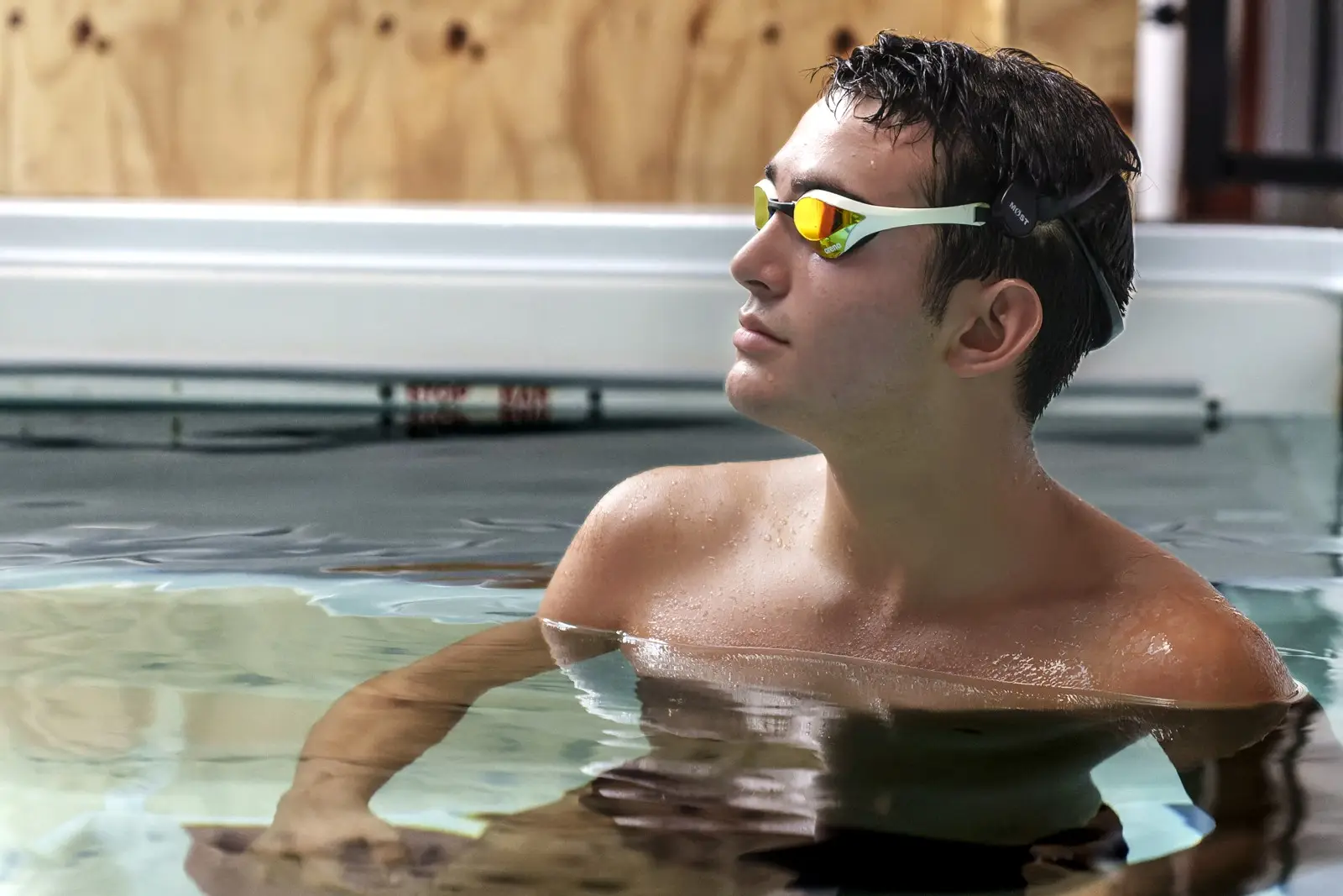 An adult swimmer resting at the wall between sets