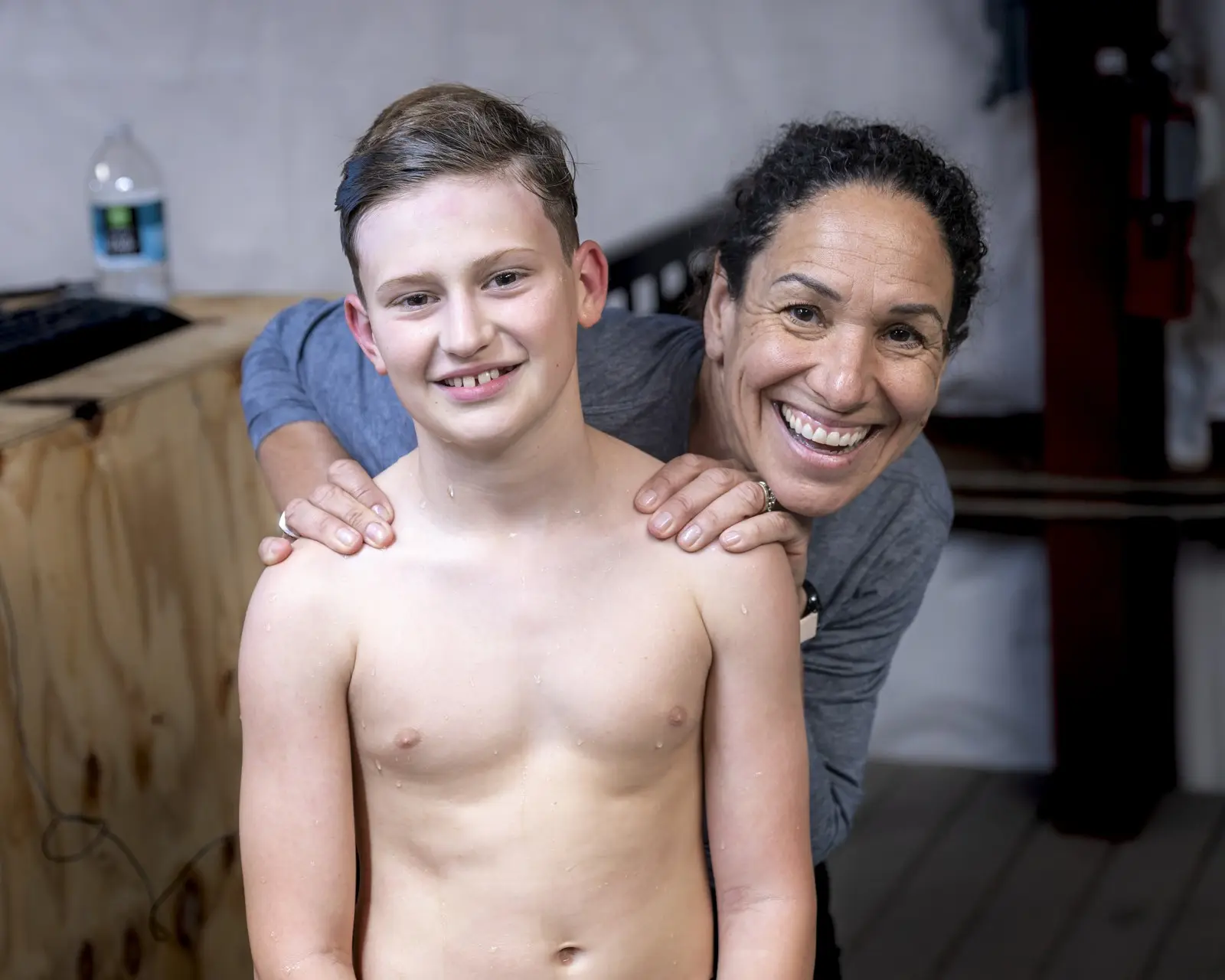 A smiling teenage swimmer with his coach