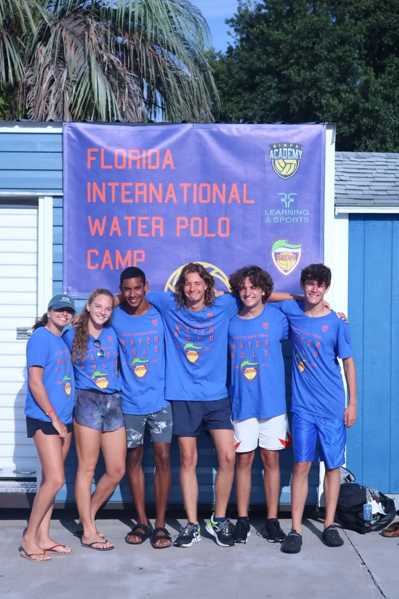 Staff in event shirts beneath the Florida International Water Polo Camp banner, 2019